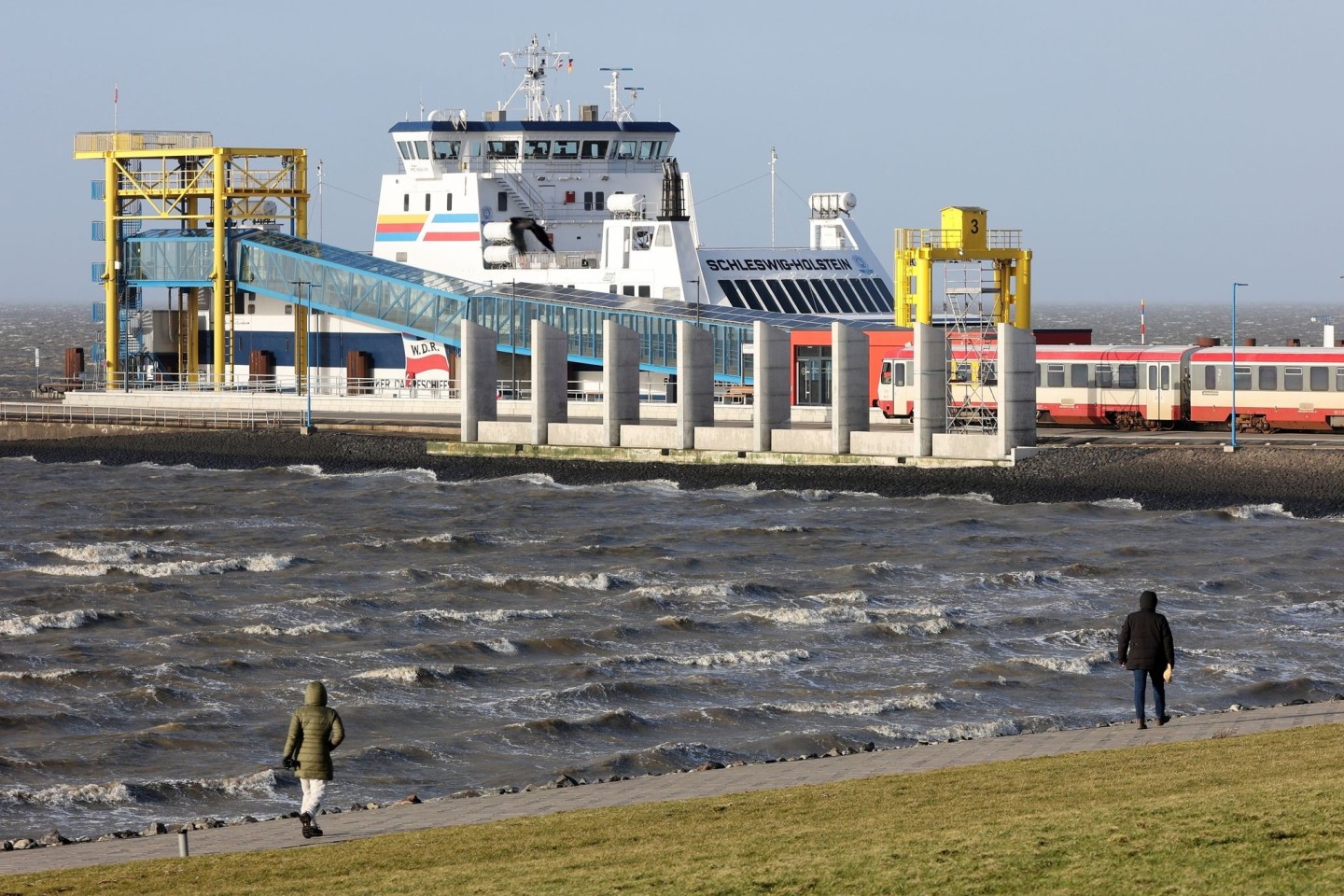 Spaziergänger sind bei stürmischem Wetter am Hafen von Dagebüll unterwegs. (Archivbild)